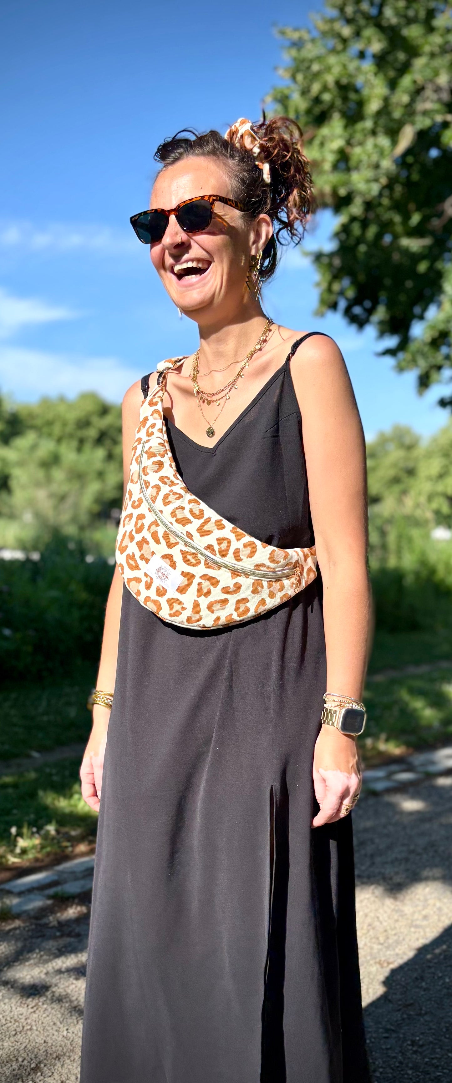 Banane léopard terracotta portée en bandoulière par une femme dans un parc ensoleillé, symbole de liberté et de style au quotidien. Ce modèle allie audace et douceur, parfait pour garder les mains libres avec élégance. Confectionnée à la main avec un tissu jacquard de qualité, elle ne se déforme pas et conserve sa tenue. Idéale pour accompagner les journées actives avec une touche de féminité bohème.
