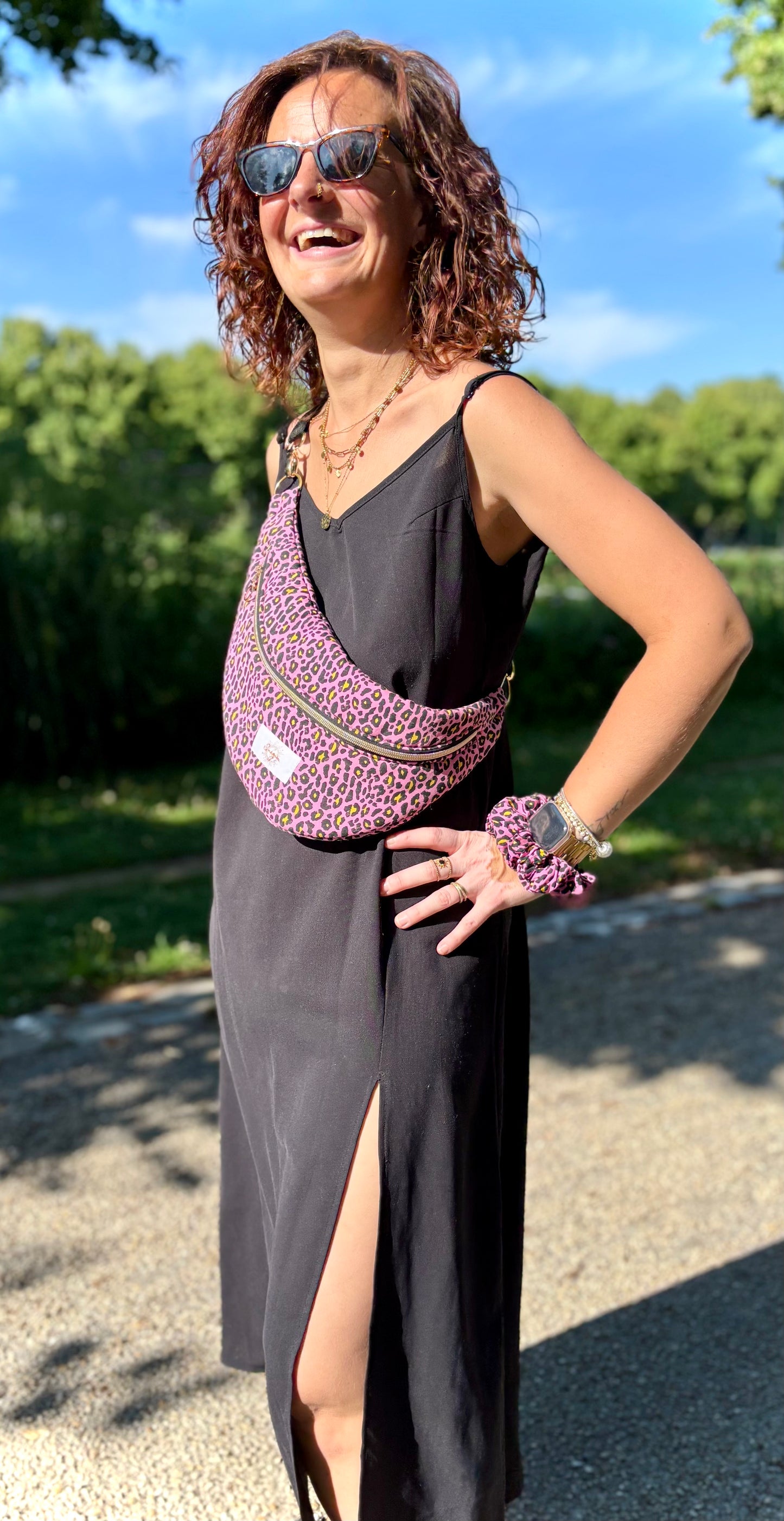 Banane rose léopard portée en bandoulière par une femme dans un parc ensoleillé, symbole de liberté et de style au quotidien. Ce modèle allie audace et douceur, parfait pour garder les mains libres avec élégance. Confectionnée à la main avec un tissu jacquard de qualité, elle ne se déforme pas et conserve sa tenue. Idéale pour accompagner les journées actives avec une touche de féminité bohème.