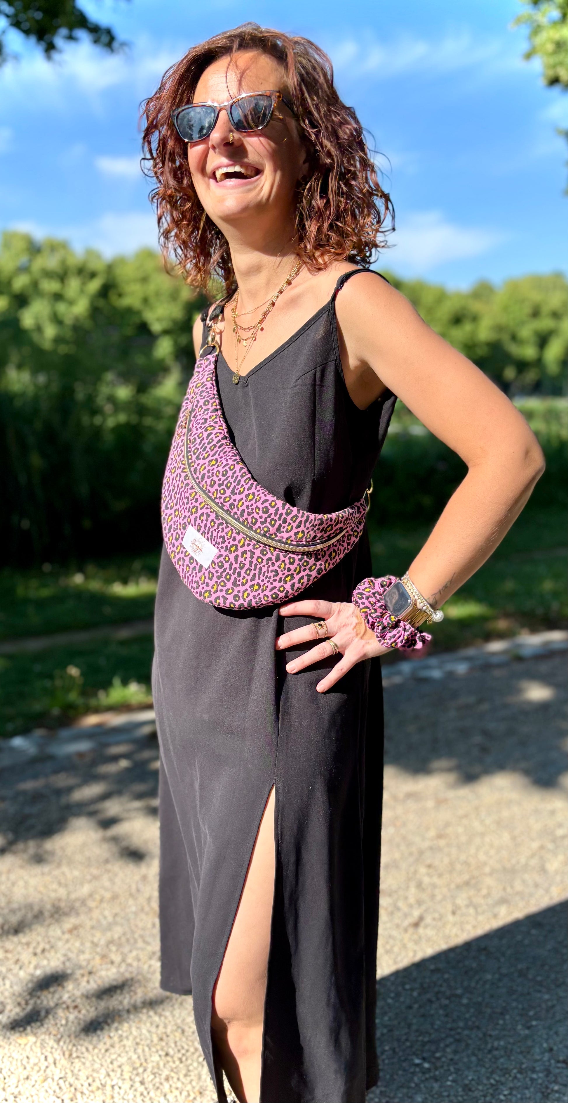 Banane rose léopard portée en bandoulière par une femme dans un parc ensoleillé, symbole de liberté et de style au quotidien. Ce modèle allie audace et douceur, parfait pour garder les mains libres avec élégance. Confectionnée à la main avec un tissu jacquard de qualité, elle ne se déforme pas et conserve sa tenue. Idéale pour accompagner les journées actives avec une touche de féminité bohème.