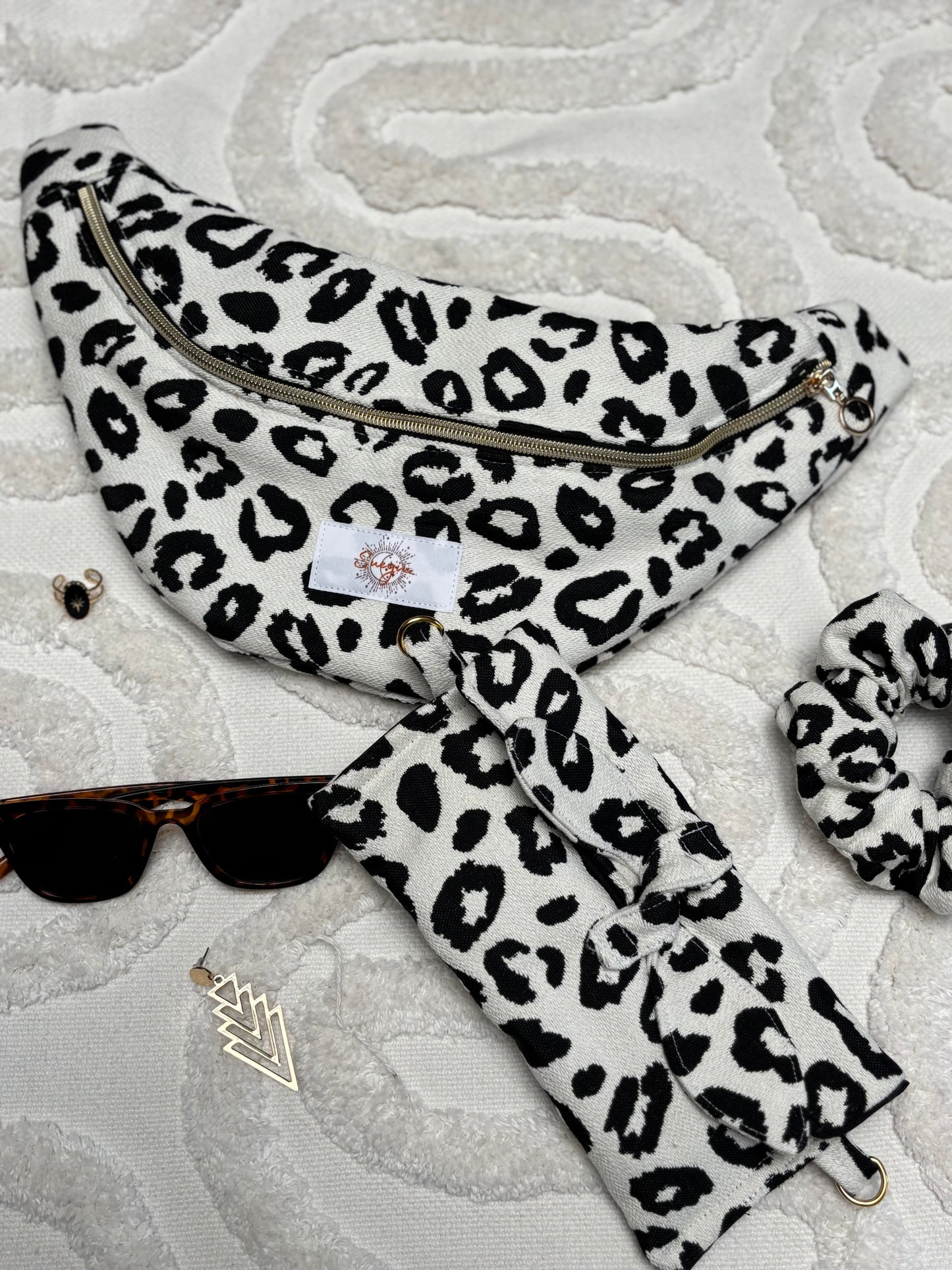 Banane léopard noir et blanc, symbole de liberté et de style au quotidien. Ce modèle allie audace et douceur, parfait pour garder les mains libres avec élégance. Confectionnée à la main avec un tissu jacquard de qualité, elle ne se déforme pas et conserve sa tenue. Idéale pour accompagner les journées actives avec une touche de féminité bohème.