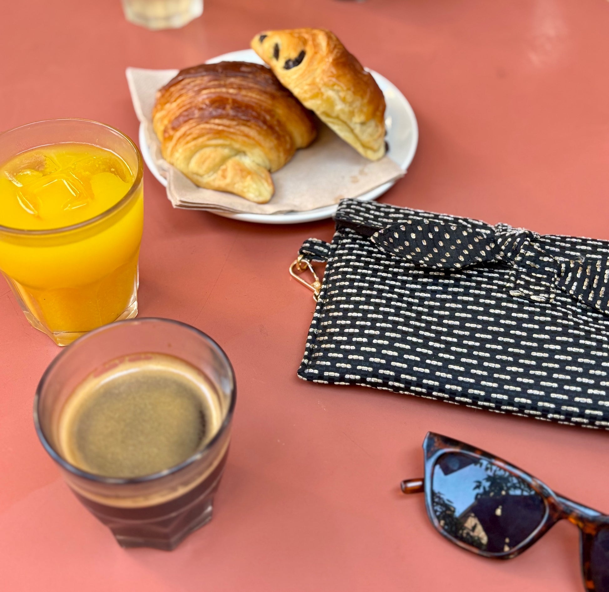 Trousse noire Alma de SueGiu posée à plat, avec sa forme rectangulaire et ses détails sobres et élégants. Tissu texturé noir profond, fermeture éclair dorée, ambiance petit déjeuner et chic.