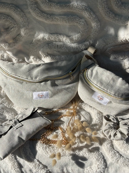 Banane beige pailletée, symbole de liberté et de style au quotidien. Ce modèle allie audace et douceur, parfait pour garder les mains libres avec élégance. Confectionnée à la main avec un tissu jacquard de qualité, elle ne se déforme pas et conserve sa tenue. Idéale pour accompagner les journées actives avec une touche de féminité bohème.
