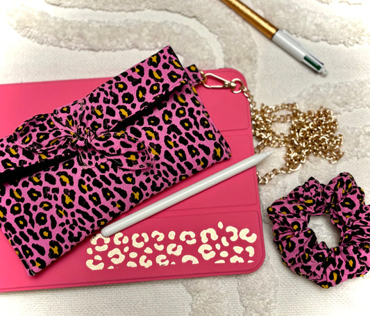 Trousse et chouchou assortis en tissu léopard rose de la collection Bohémia par SueGiu, posés sur une tablette rose avec stylet, chaîne dorée et stylo, dans une ambiance féminine, tendance et pratique.